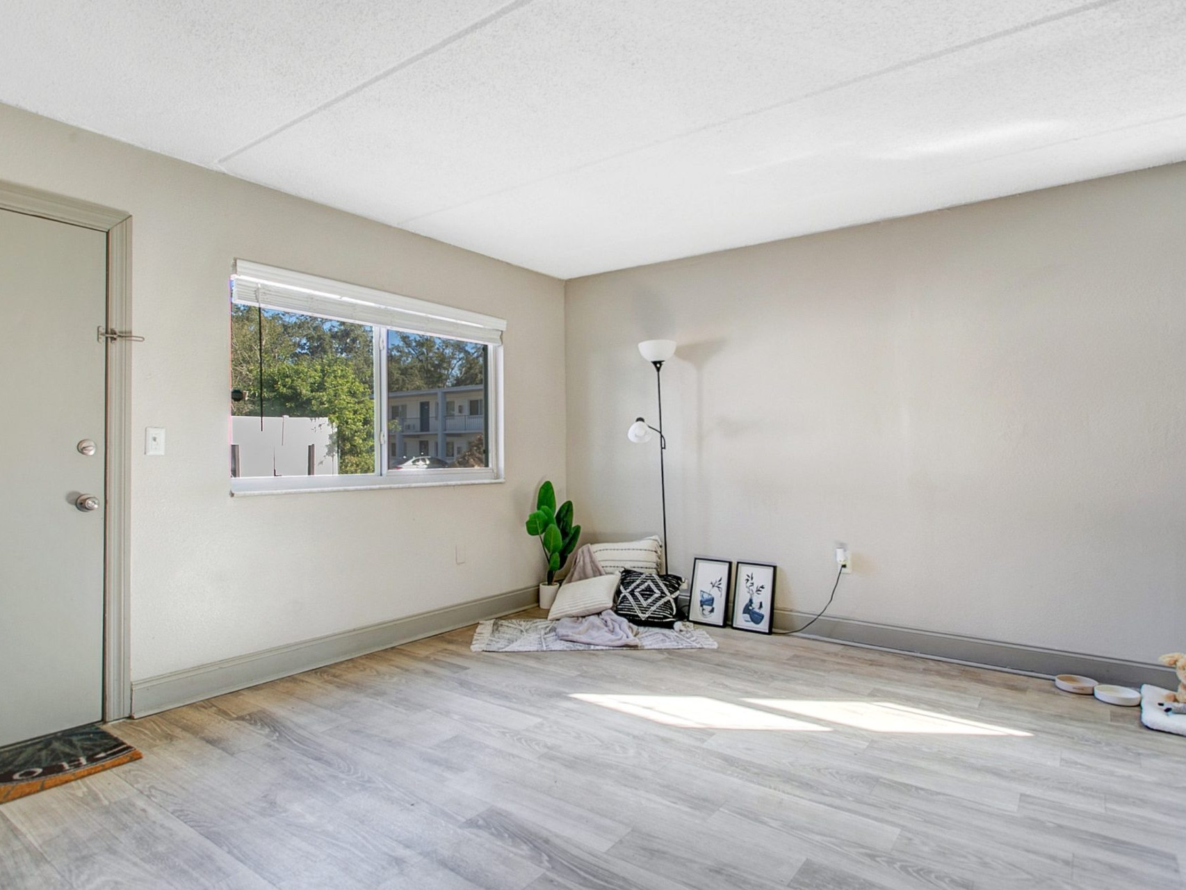 A living room with hardwood-style flooring and a large window.