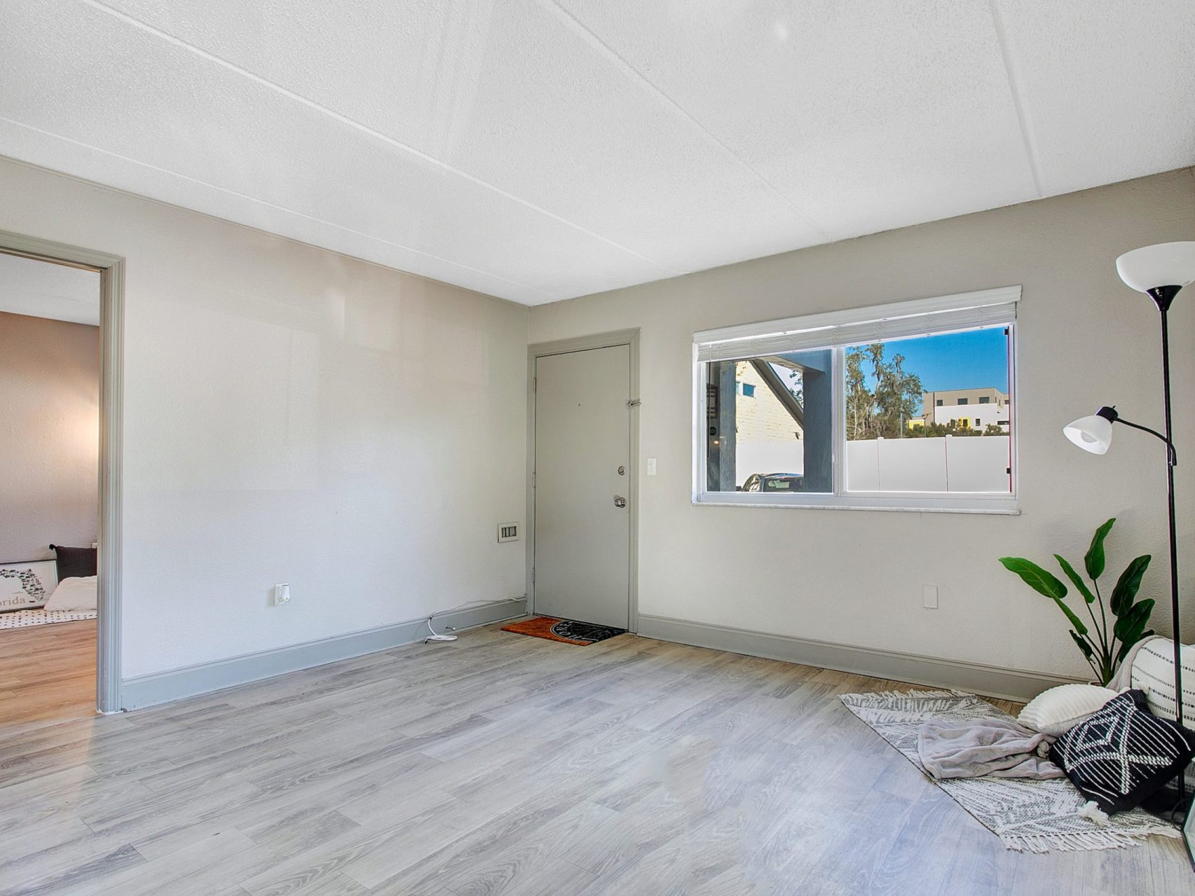 A living room near the entryway with an large window and access to a side room.