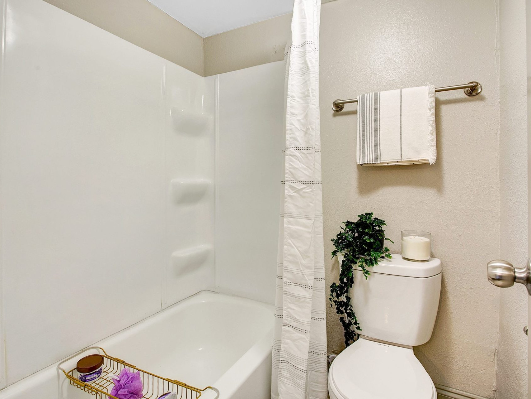 A bathroom with a shower/tub combination, a toilet, and a towel bar.