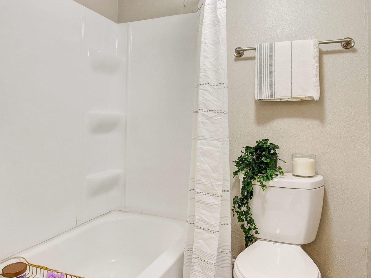 A bathroom with a shower/tub combination, a toilet, and a towel bar.