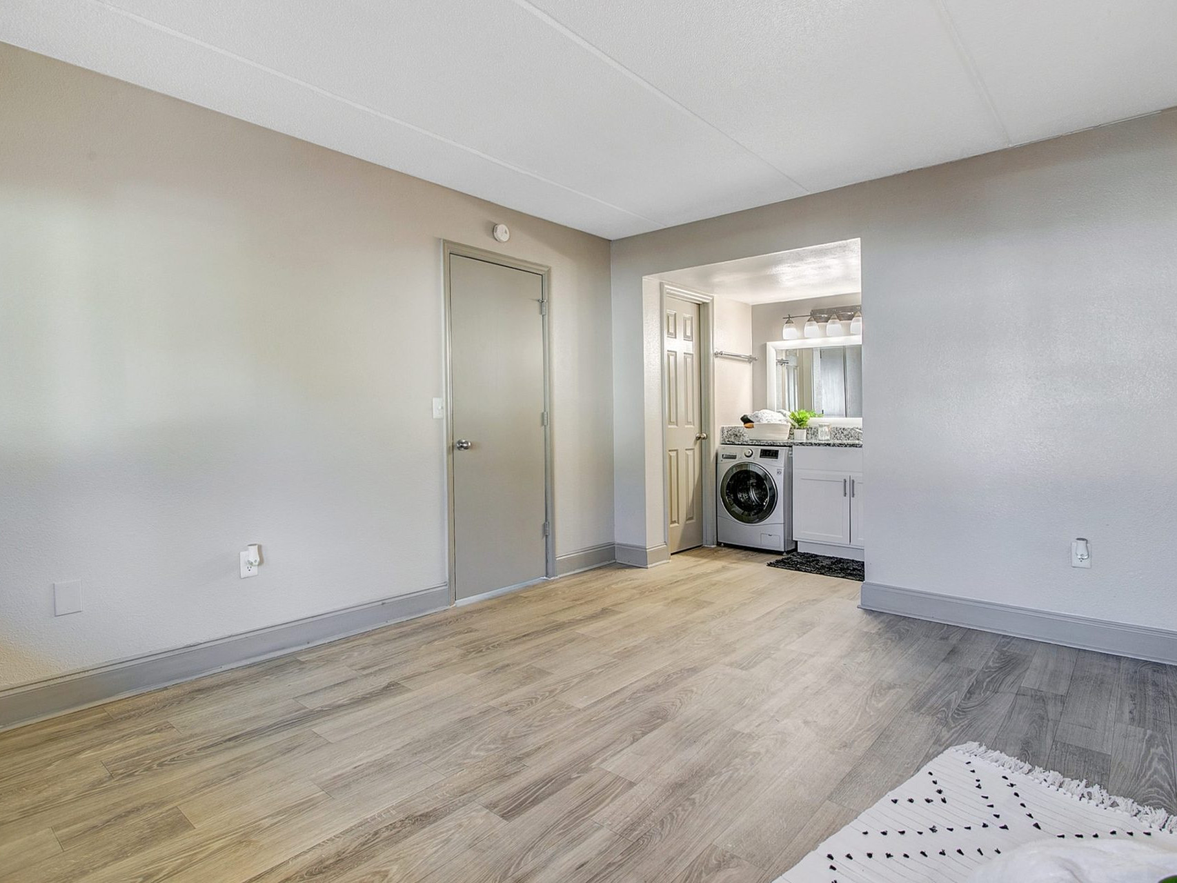 A living room with hardwood-style flooring, an entryway, and a laundry area with a washer/dryer.
