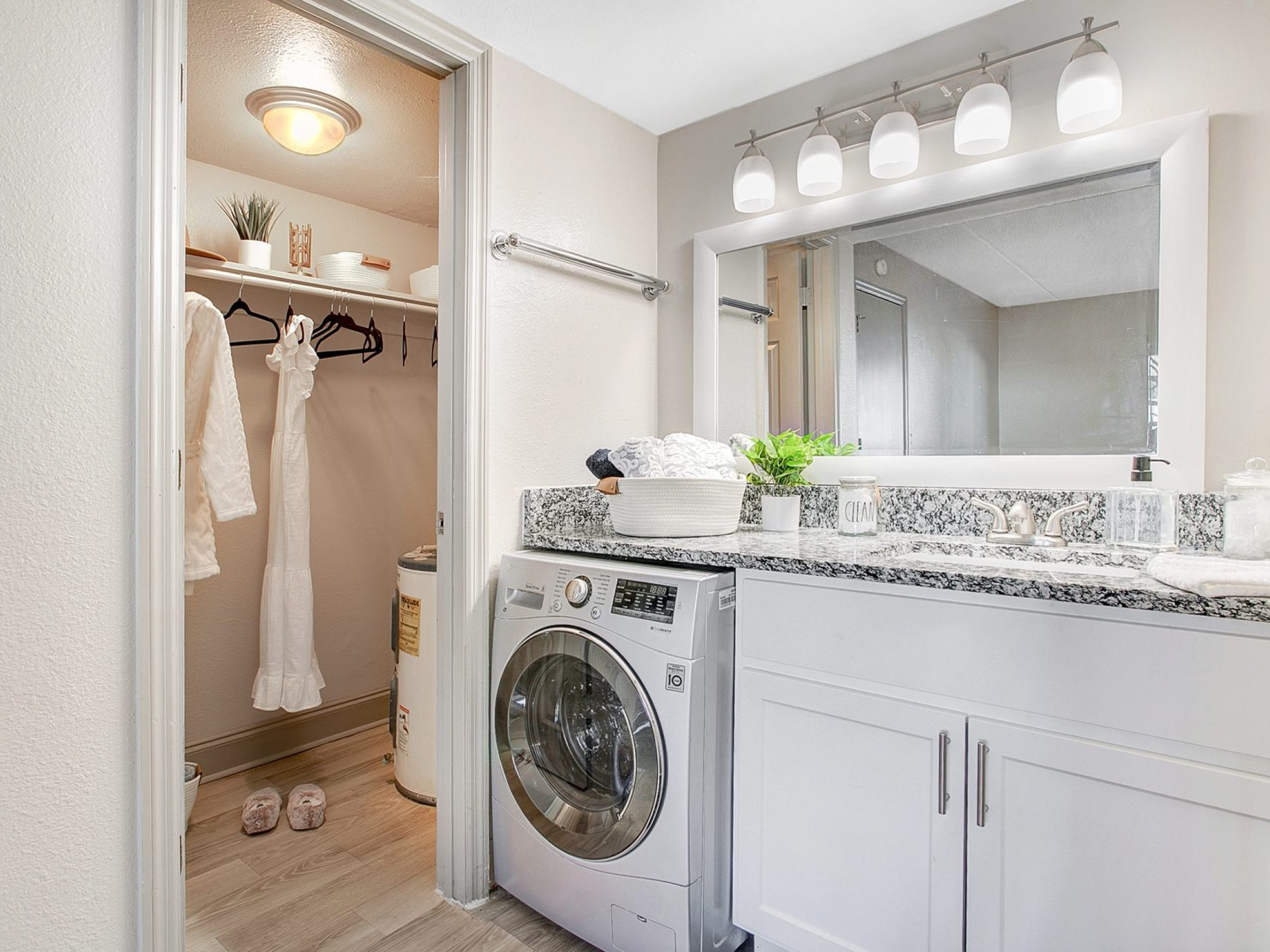A laundry are with a modern sink, built-in cabinets, washer/dryer and access to a walk in closet.