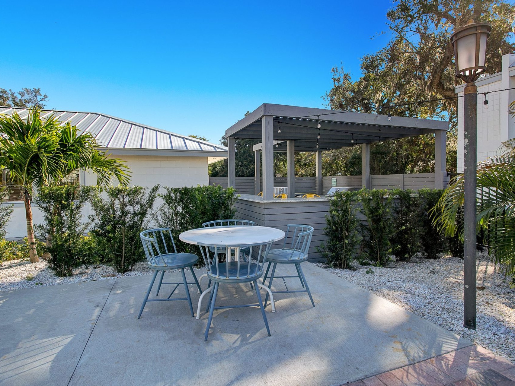 An outdoor picnic area with 4 chairs and a table near the community barbecue area at SoDo Flats.